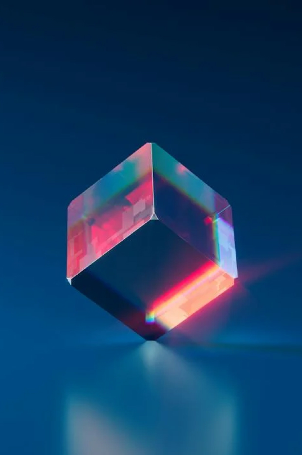 Apstraktni, geometrijski oblikovan kristal koji reflektuje živopisna crvena i plava svetla na tamnoj pozadini, pružajući osećaj moderne umetnosti ili dizajna.
