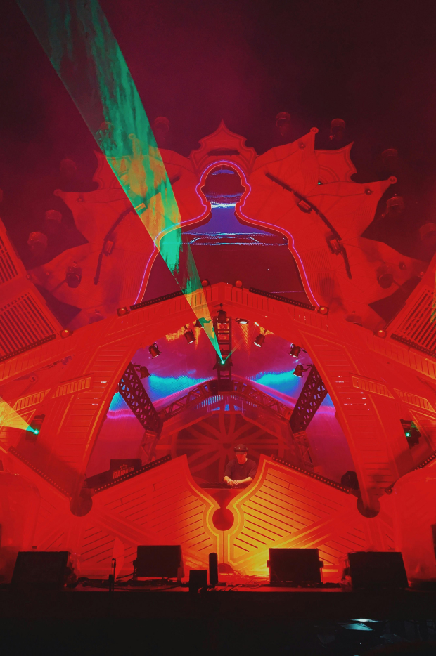 Impresivna bina na muzičkom festivalu, sa živopisnim laserskim svetlima i neonskim obrisima ljudske figure, stvarajući elektrifikujuću atmosferu za nastup uživo.