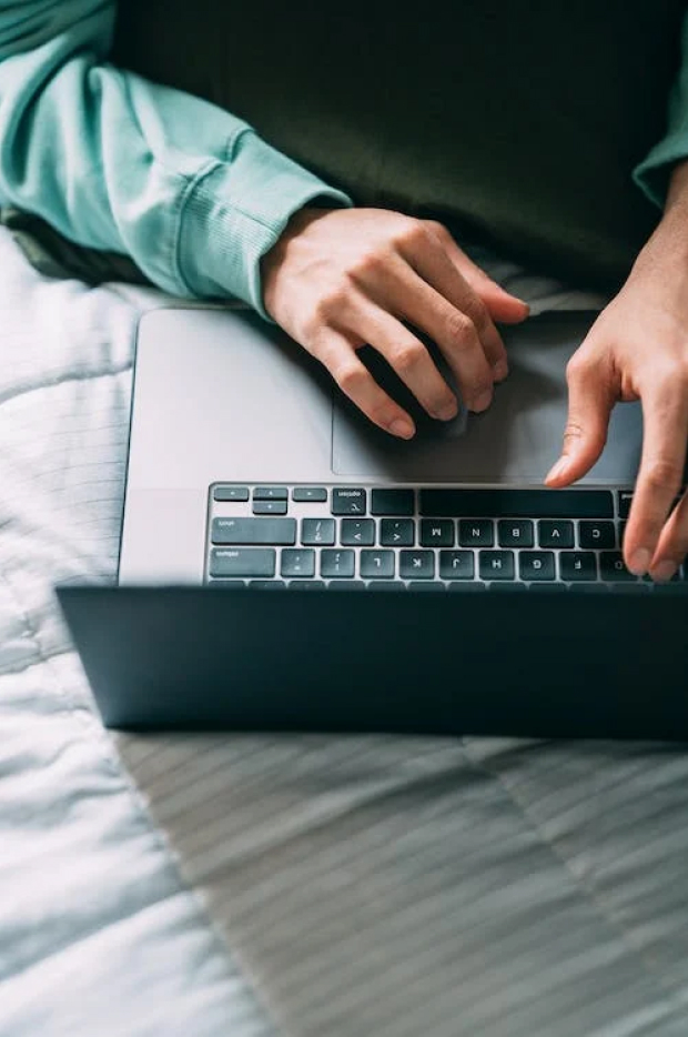 Krupni kadar ruku osobe koja kuca na tastaturi laptopa, sugerišući rad, komunikaciju ili pregledanje interneta, sa fokusom na interakciju između korisnika i uređaja.
