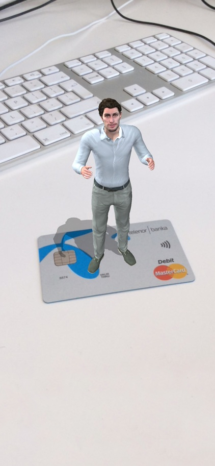 Prikaz proširene stvarnosti (AR) male animirane figure čoveka koji stoji na vrhu kreditne kartice, pored tastature, što ukazuje na vizuelizaciju ličnih finansija i usluge onlajn bankarstva.